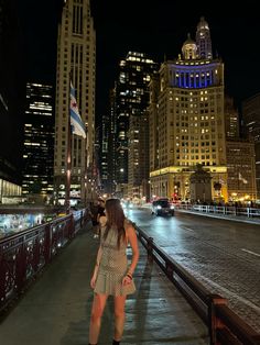 a woman standing on a bridge in the city at night