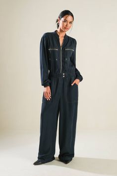 A solid woven jumpsuit featuring front zipper/button closure, pockets, long sleeve, and wide leg Details: Self: 100% Tencel Size & Fit - Model is 5`9" And Wearing Size Small- Measurements Taken From Size Small- Approx. Length: 62"- Approx. Inseam: 29" Solid Denim Jumpsuit With Pockets For Work, Long Sleeve Overalls With Side Pockets For Fall, Spring Long Sleeve Jumpsuits And Rompers With Side Pockets, Fall Utility Denim Jumpsuit With Side Pockets, Fall Utility Jumpsuits And Rompers With Relaxed Fit, Long Sleeve Utility Jumpsuit For Work, Utility Long Sleeve Jumpsuits For Work, Utility Long Sleeve Jumpsuits And Rompers For Workwear, Fall Denim Jumpsuit With Side Pockets