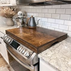 a stove top sitting inside of a kitchen next to a microwave and countertop with pots on it