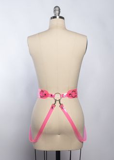 The statement-making belt in neon PVC turns heads with it's flattering design. Sits at the natural waist. Belt fastens buckle in front. Detachable hip straps clip at the front and back and follow the natural curves of the body. A perfect layering piece. Belt is 2" wide. Fit is adjustable with buckles and straps. Silver-toned nickel plated steel hardware. Shown in translucent neon pink PVC (UV/blacklight reactive!) Also available in neon orange (UV), lime green, clear, silver glitter, and black. Heart Harness, Fashion Harness, Harness Belt, Body Harness, Natural Curves, Wide Belt, Neon Orange, Silver Glitter, Backless Dress Formal