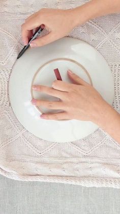 a woman is using scissors to cut the ends of two pieces of paper on a plate