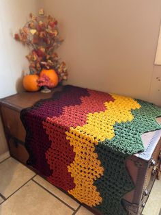 a crocheted blanket sitting on top of a trunk