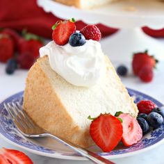 a slice of angel food cake with whipped cream and berries on the plate next to it