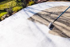 a person with a mop on top of a cement slab in the middle of a yard