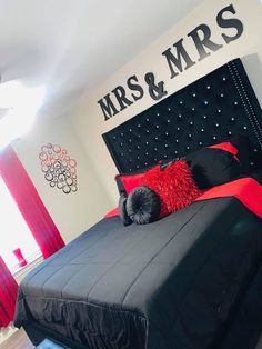 a black and red bed in a bedroom with the name mrs & mr's on the wall