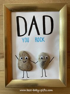 two rocks with the words dad you rock written on them in front of a gold frame