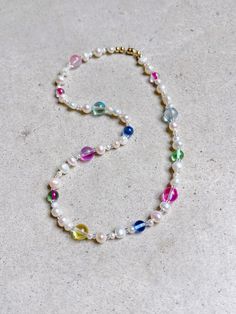 a multicolored beaded necklace on a white surface