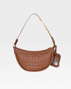 Elevate your style with this chic and functional accessory. Featuring a curved silhouette and rich caramel hue, this bag is made from high-quality vegan leather, offering the perfect mix of luxury and durability. Perfect for any occasion, the Caramel Cutie Shoulder Purse is your new go-to for adding a touch of elegance to any outfit. Make it yours today. Daily Use Cognac Shoulder Bag With Gold-tone Hardware, Designer Suede Shoulder Bag With Gold-tone Hardware, Suede Shoulder Bag With Gold-tone Hardware, Luxury Suede Shoulder Bag With Gold-tone Hardware, Orange Crossbody Shoulder Bag With Gold-tone Hardware, Suitcase Set, Crescent Shape, Crocodile Skin, Caramel Color