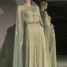 Mint Green Elegance: The mint green hue exudes freshness and sophistication, ensuring you stand out with a unique and stylish look. Luxury Beaded Detailing: Intricate beaded detailing adds a touch of opulence and glamour, enhancing the gown's allure. Elegant Cape: The flowing cape introduces an element of drama and grace, elevating the gown's overall design. Ideal for Arabic Women: Tailored for Arabic women, ensuring you exude charm and grace amidst the celebration. Perfect for Long Wedding Part Green Sequined Evening Dress For Banquet, Green Sequined Evening Dress For Banquets, Green Sequin Dress For Banquet, Embellished Green Gown For Banquet, Green Sequined Gown For Reception, Green Sequined Reception Gown, Green Embellished Evening Dress For Wedding, Long Sleeve Embellished Green Gown, Embellished Long Sleeve Green Gown