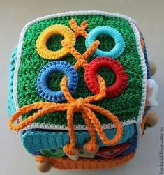 a crocheted box with an olympic symbol on the front and sides, decorated in multi - colored yarns