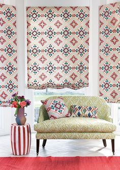 a living room filled with furniture and windows covered in roman shades on the windowsill