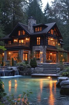 a large house sitting on top of a lush green hillside next to a lake at night