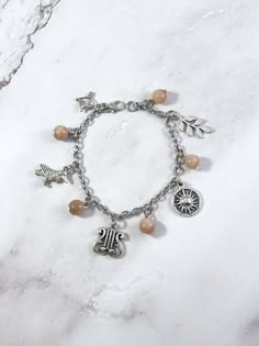 This Apollo themed charm bracelet is the perfect accessory to showcase your love for the Greek myths in a subtle way. Apollo is the Greek god of music, the sun, light, archery, and art. Charms included: Bow and Arrow Raven Lyre Sun Laurel Branch 5 sunstone beads are also included. Comes in three sizes: Small: 6.5 inches (with extra rings at the end to expand up to 7.5 inches.) Standard: 7.5 inches Large: 8.5 inches Secures with a lobster clasp. Made with lead and nickel free zinc alloy. Comes in Apollo Jewelry, Percy Jackson Jewelry, Greek Mythology Jewelry, Laurel Branch, Mythology Jewelry, God Of Music, Greek Gods And Goddesses, Bow And Arrow, Greek God