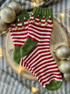 a pair of red and white striped socks sitting on top of a wooden slice next to christmas ornaments