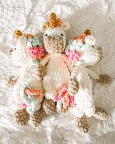 two crocheted stuffed animals laying next to each other on a white bed sheet