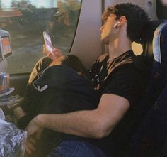 two people sitting on an airplane looking at their cell phones while they are in the seat