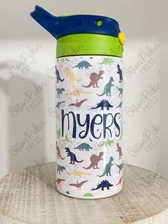 thermos bottle with dinosaurs on it is sitting on top of a wooden table