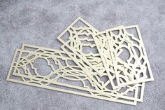 four pieces of laser cut wood sitting on top of a gray carpeted floor next to each other