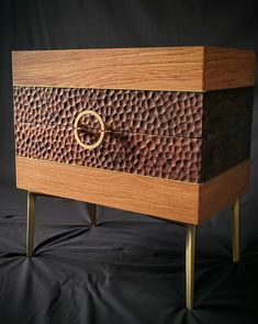 a wooden chest with an oval handle on it's front and side legs, against a black background