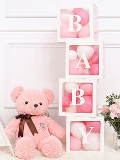 a pink teddy bear sitting next to blocks that spell out the word b is for baby