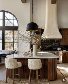 a kitchen with two stools and an island in the middle of it, surrounded by windows