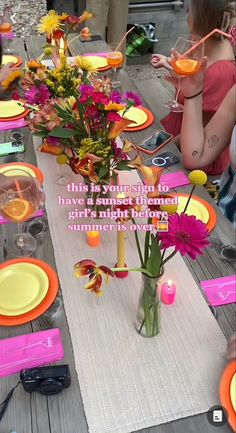 a group of people sitting around a wooden table with plates and flowers in vases