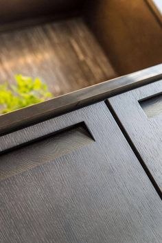 a close up view of the handles on a wooden cabinet with green plants in the background