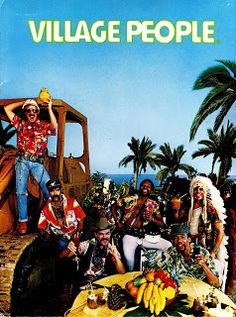 a group of people sitting around a table with fruit on it and the words village people