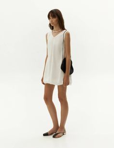 Elevate your wardrobe with our exquisite white balloon dress, crafted from premium viscose fabric that showcases a distinctive crinkled texture. Embracing a fashion-forward approach, this dress showcases a flattering v-neckline and a sleeveless silhouette, while its chic shorter length ensures suitability for any event. The timeless black hue exudes versatility, enabling effortless styling and making it an essential piece for your ensemble. Complete the look by pairing it with our faux-leather j Chic Crinkle Texture Dresses For Vacation, Chic Vacation Dresses With Crinkle Texture, Chic V-neck Dress With Crinkle Texture, V-neck Crinkle Texture Summer Dress, V-neck Summer Dress With Crinkle Texture, Summer V-neck Dress With Crinkle Texture, Chic V-neck Viscose Dress For Summer, Chic White V-neck Daywear Dress, Chic White V-neck Dress For Daywear