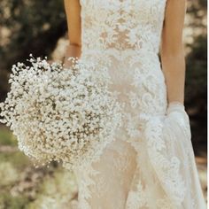 a woman in a wedding dress holding a bouquet of baby's breathflowers