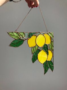 a stained glass hanging decoration with lemons on it's side and green leaves