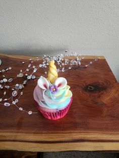 a cupcake decorated with icing and a unicorn's horn on a wooden table