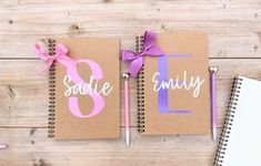 two personalized notebooks with pink and purple ribbon on them, one has the letter e