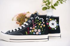 a pair of black sneakers with flowers painted on them