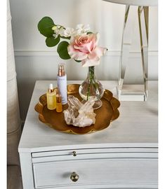 a vase with flowers and perfumes on a tray next to a chair in a room