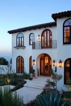 a large white house with lots of windows and lights on the front entrance to it