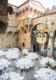 tables and chairs are set up in front of an old building with arched doorways