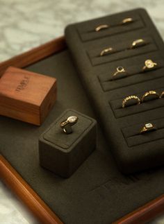 an assortment of rings and jewelry on display in a wooden box with black velvet pad