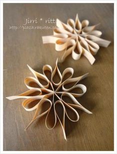 two paper flowers sitting on top of a wooden table