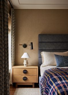 a bed sitting next to a night stand with a lamp on it's side