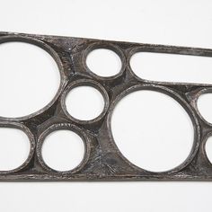 an old metal object with holes in the middle on a white surface, that appears to have been cut into smaller circles