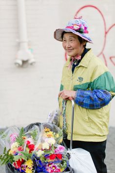 an older woman holding a cane with flowers in it and wearing a hat on her head