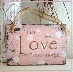 a pink wooden sign with the word love painted on it