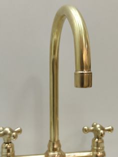 two brass faucets on the side of a white wall