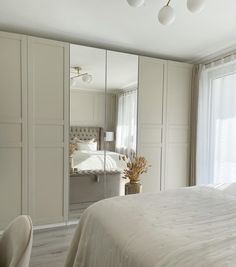 a bedroom with a bed, mirror and chairs