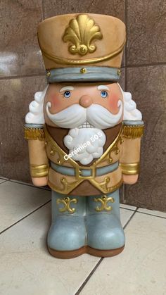 a ceramic figurine of a nutcracker wearing a gold hat and blue pants