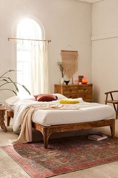 a bed sitting on top of a rug next to a wooden dresser and window in a bedroom