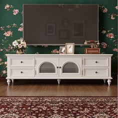 a white entertainment center with floral wallpaper and a flat screen tv mounted on the wall