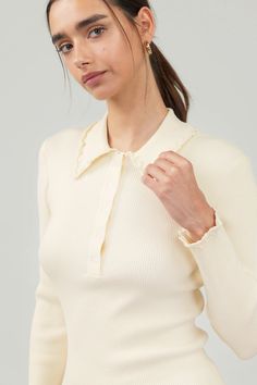 Introducing our Ivory Long Sleeve Top, a modern twist on a classic polo sweater. This soft and cozy knit features a tidy collar with playful ruffle detailing. Complete with a button placket and long sleeves, it's the perfect combination of sophistication and comfort. polo collar ruffle trim button placket long sleeves ribbed true to size model is wearing a small - Model Stats: 72% viscose 28% polyester hand wash cold White Elegant Collared Polo Sweater, Elegant Beige Collared Polo Sweater, Spring Collared Fine Knit Polo Sweater, Spring Fine Knit Collared Polo Sweater, Elegant Sweater With Ribbed Collar, Cream Long Sleeve Polo Sweater With Ribbed Cuffs, Long Sleeve Cream Polo Sweater With Ribbed Cuffs, Chic White Polo Sweater For Fall, Chic Long Sleeve Fine Knit Polo Sweater