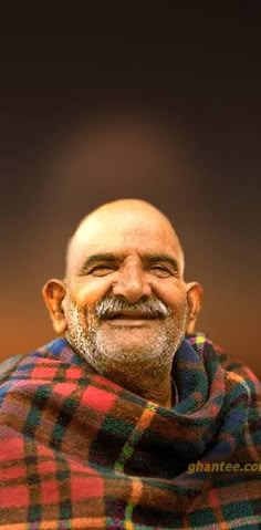 an old man with a beard and moustache wrapped in a plaid blanket looking at the camera